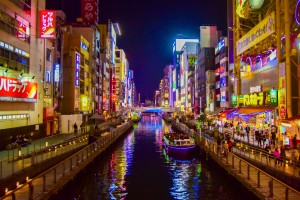 A boat floats along Osaka's Dotonbori Canal in the packed entertainment district.